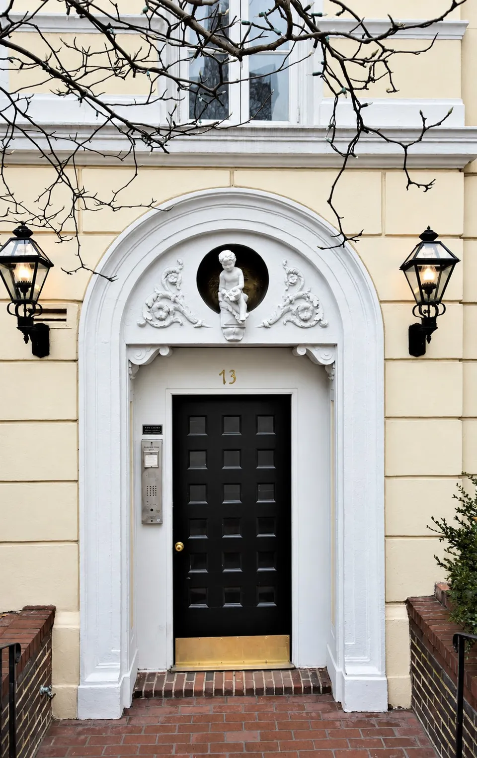 The arched entrance at No. 13, with floral ornament and a small sculptured figure above the black door.