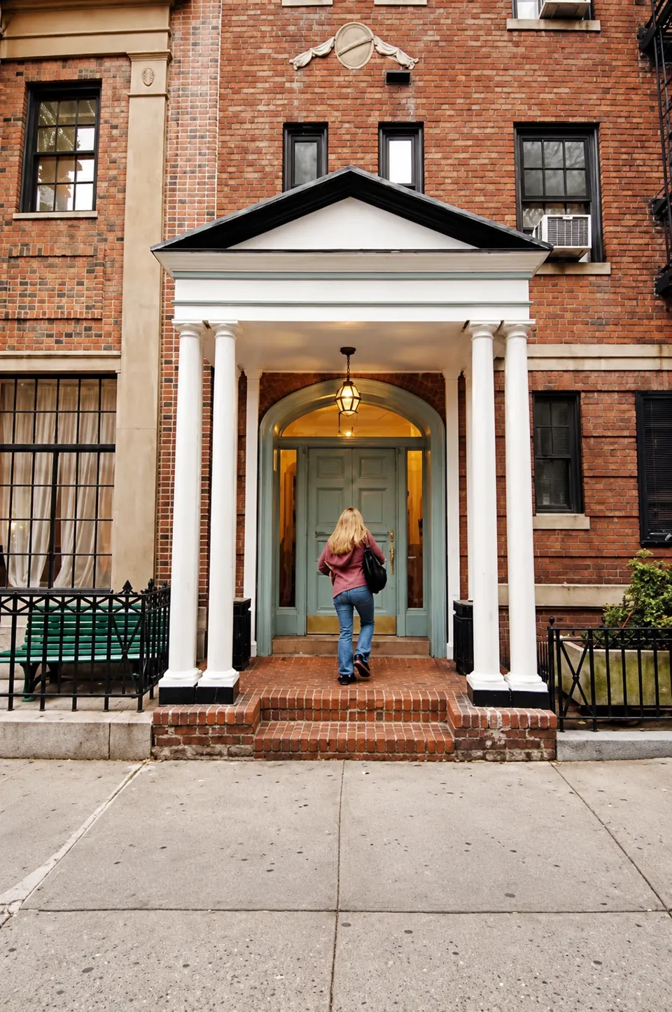 The white-columned portico and green doors at 17 Gramercy Park South, with a person entering.