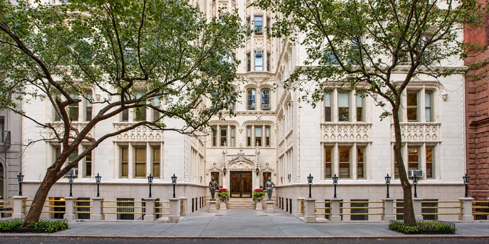 The pale terra-cotta facade and recessed entrance of 36 Gramercy Park East, framed by street trees.