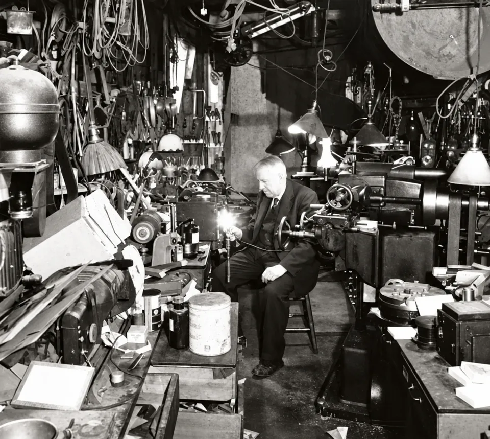 Edward Ringwood Hewitt seated among the equipment in a workshop.