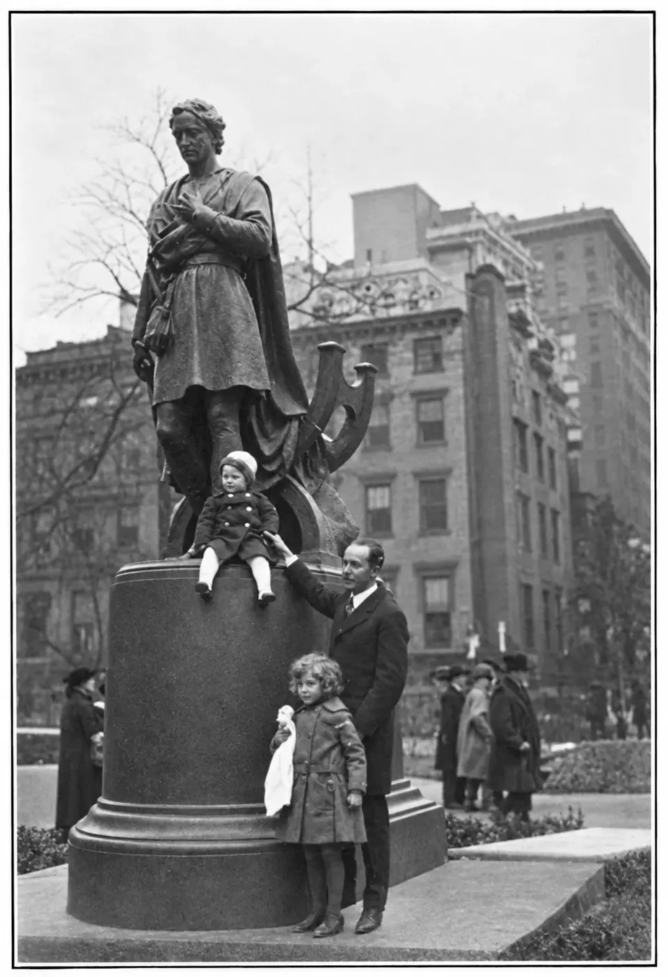 Booth’s grandson stands at the statue with two small great-grandchildren, one seated on the pedestal.