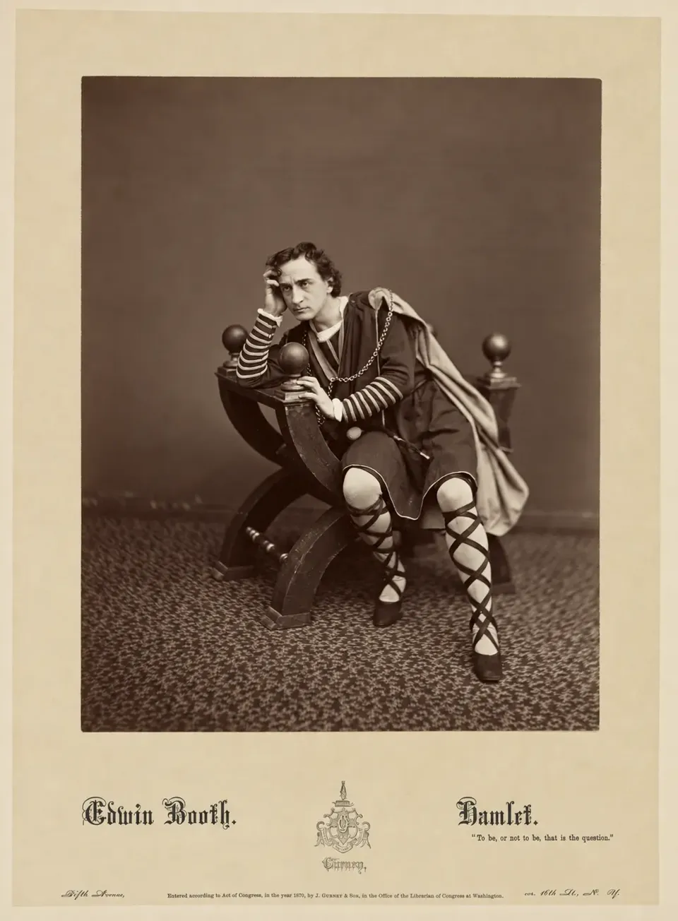 Edwin Booth in Hamlet costume, seated sideways and leaning on the back of a chair.