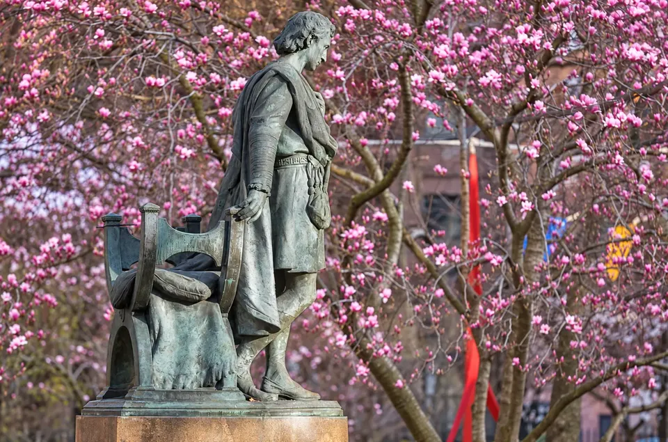 Edwin Booth as Hamlet, seen beside his bronze chair against flowering trees in Gramercy Park.