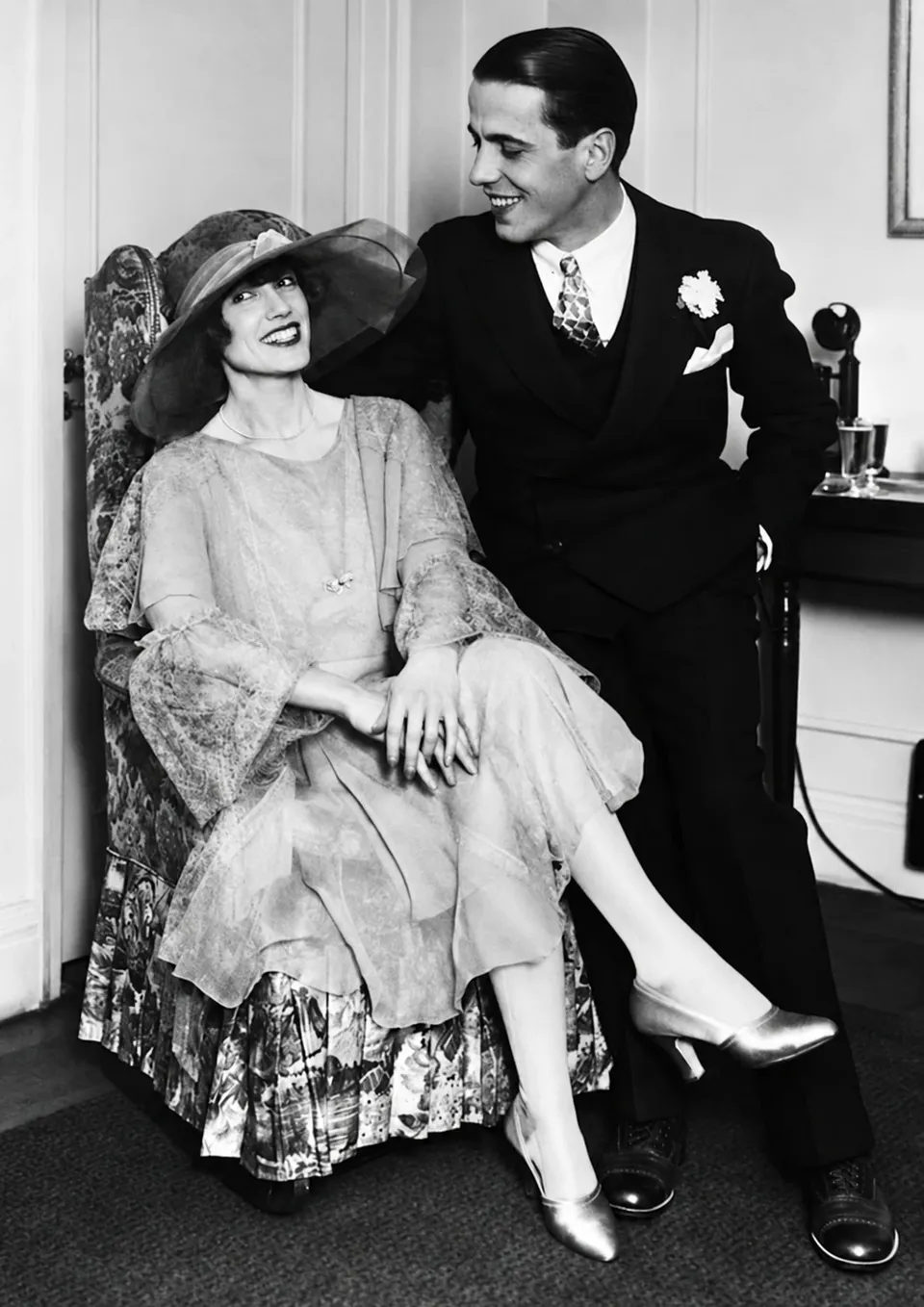 Helen Menken seated beside Humphrey Bogart, who is standing with an arm around her chair.