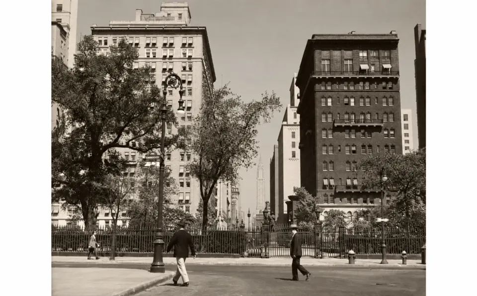 Historic view across Gramercy Park toward Lexington Avenue, with the hotel at left, One Lexington Avenue at right and pedestrians in the foreground.