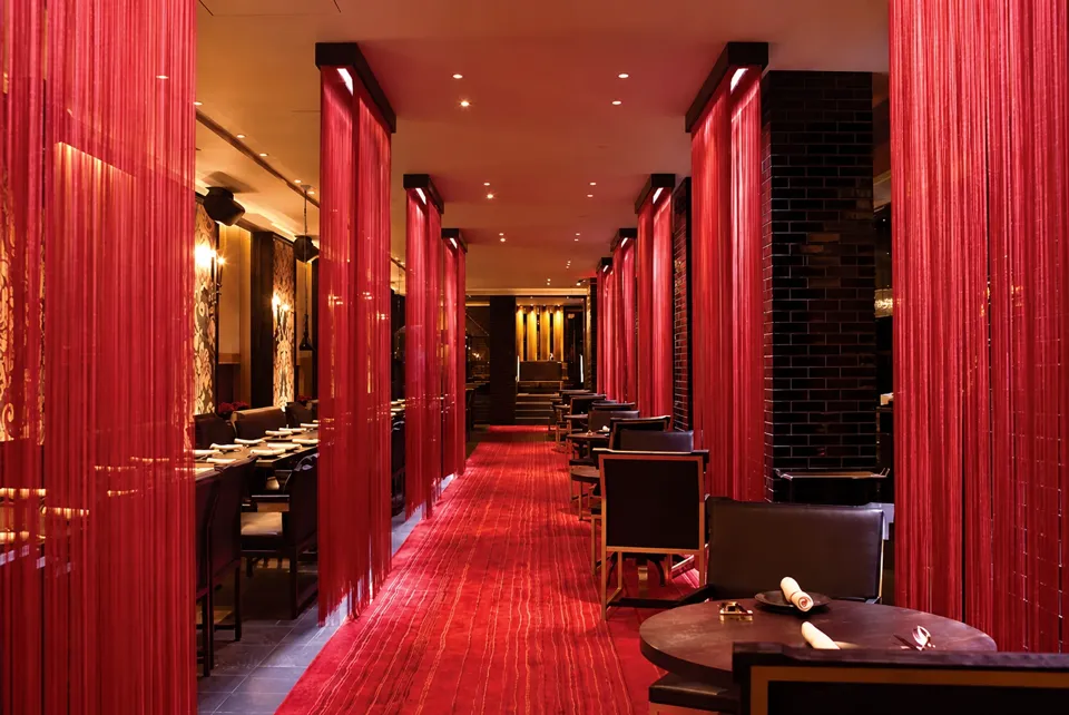 Wakiya dining room with red curtains, dark tables, and a red carpet.