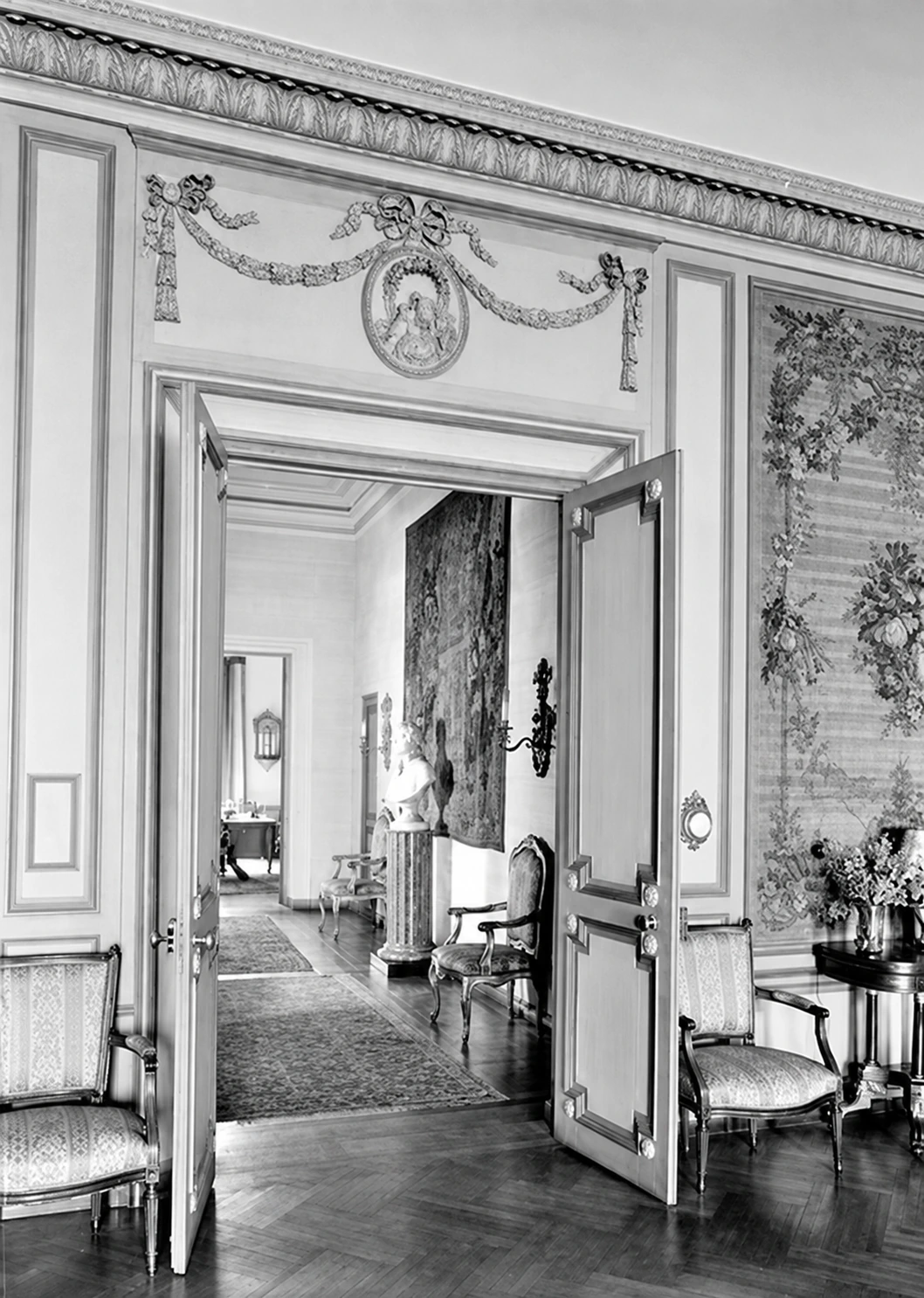 A view through tall paneled doorways across the stair hall toward another room.