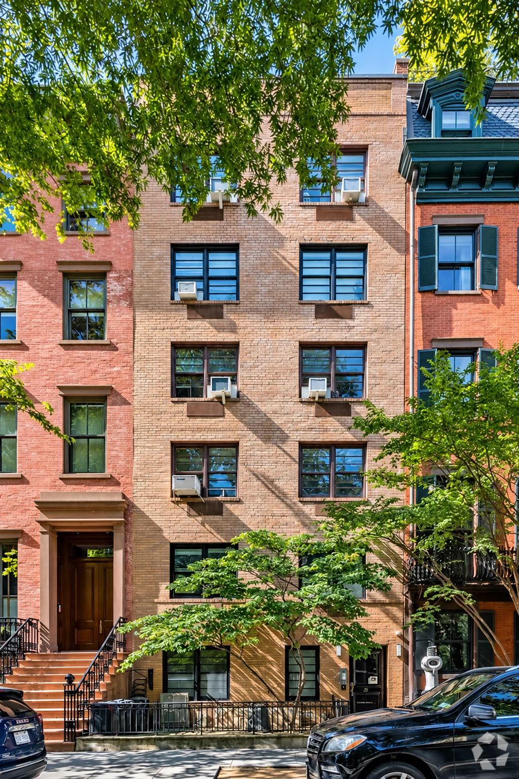 The present brick façade of No. 21, framed by older houses and the trees of Gramercy Park.