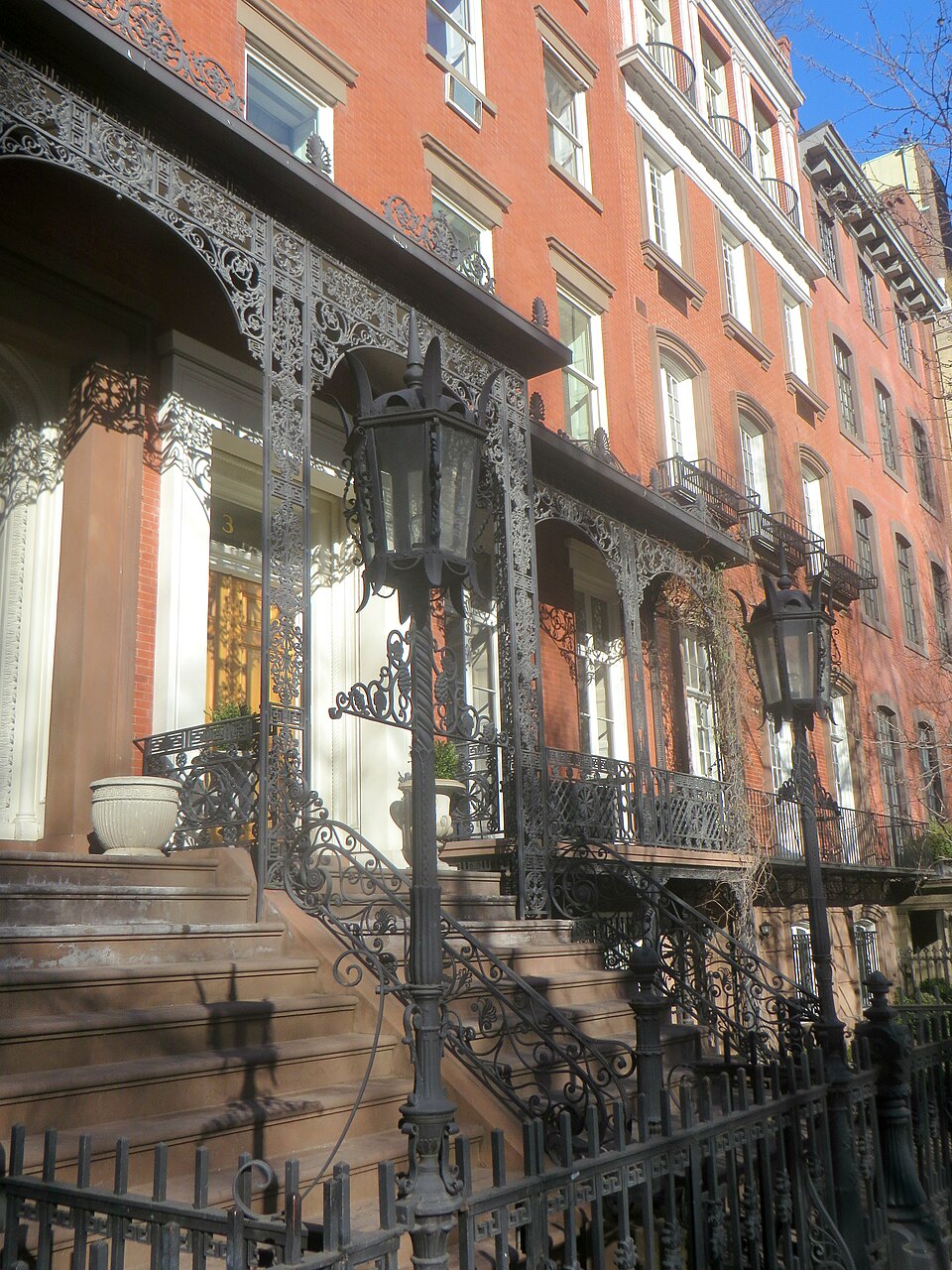 A close view looking along No. 3’s cast-iron porch in winter sunshine, with the number 3 above the entrance, slender ornamented columns and the brick façade above.
