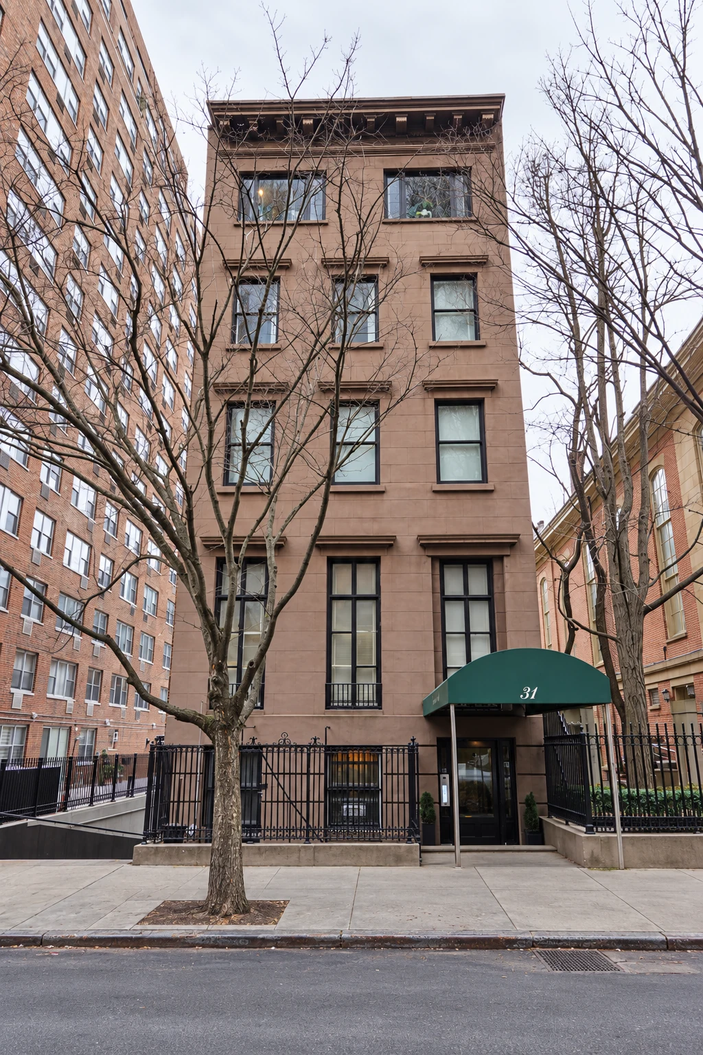 The brownstone façade of 31 Gramercy Park South, with broad upper windows, a cornice, and a green entrance canopy.