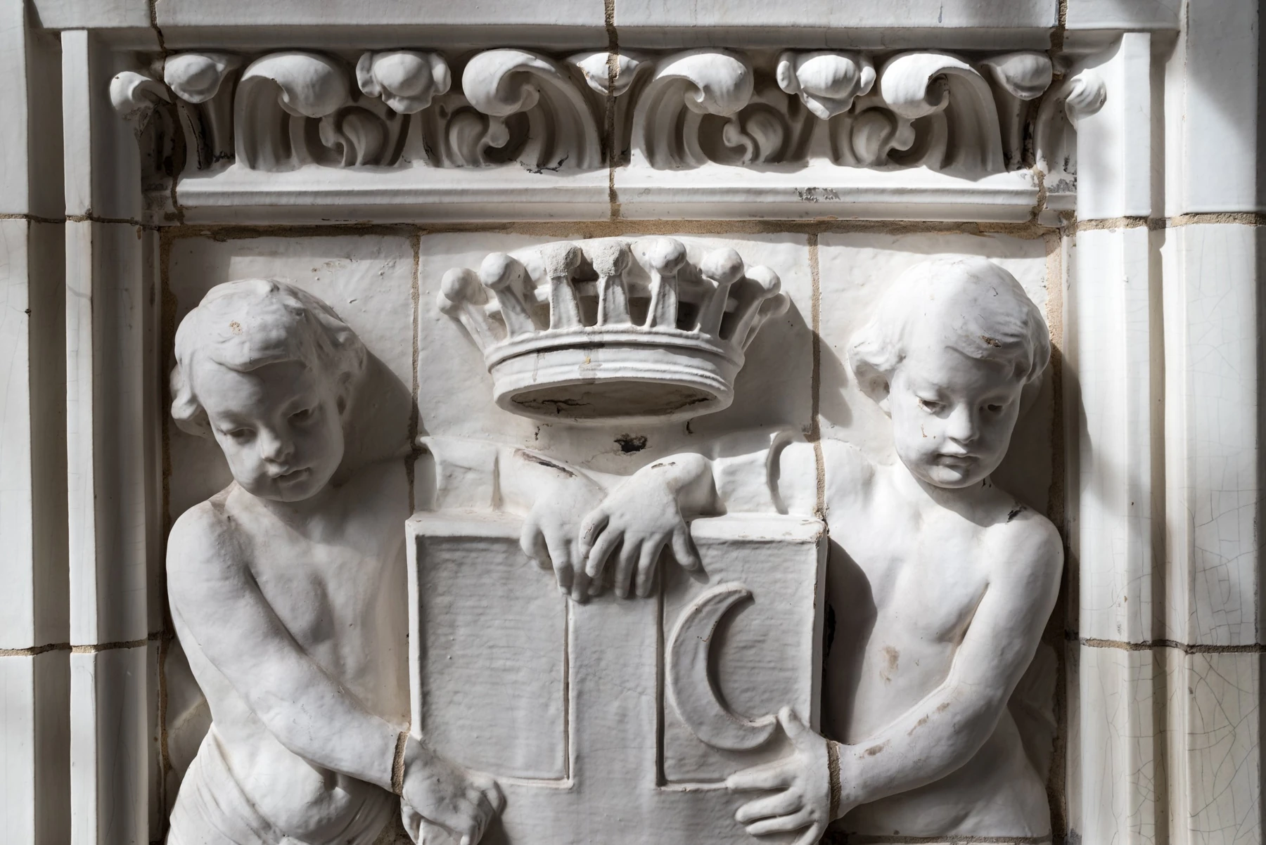 Two sculpted children flank a crowned shield in the glazed terra cotta of 36 Gramercy Park East.