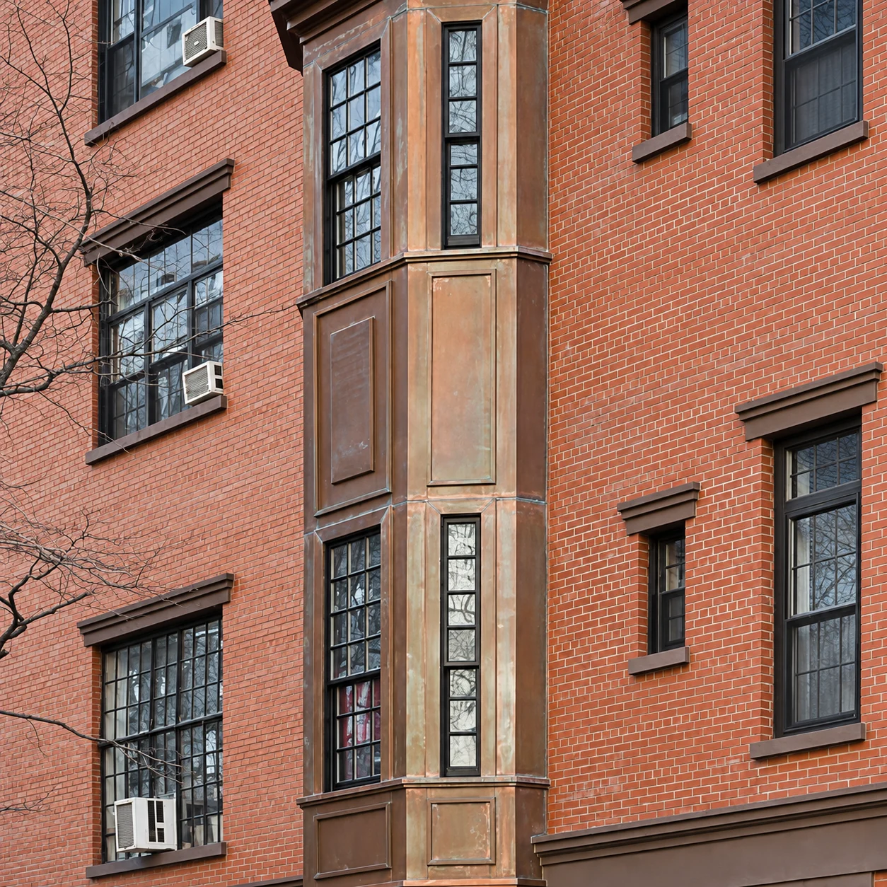 Close view of copper-clad projecting window bays against the red-brick façade.
