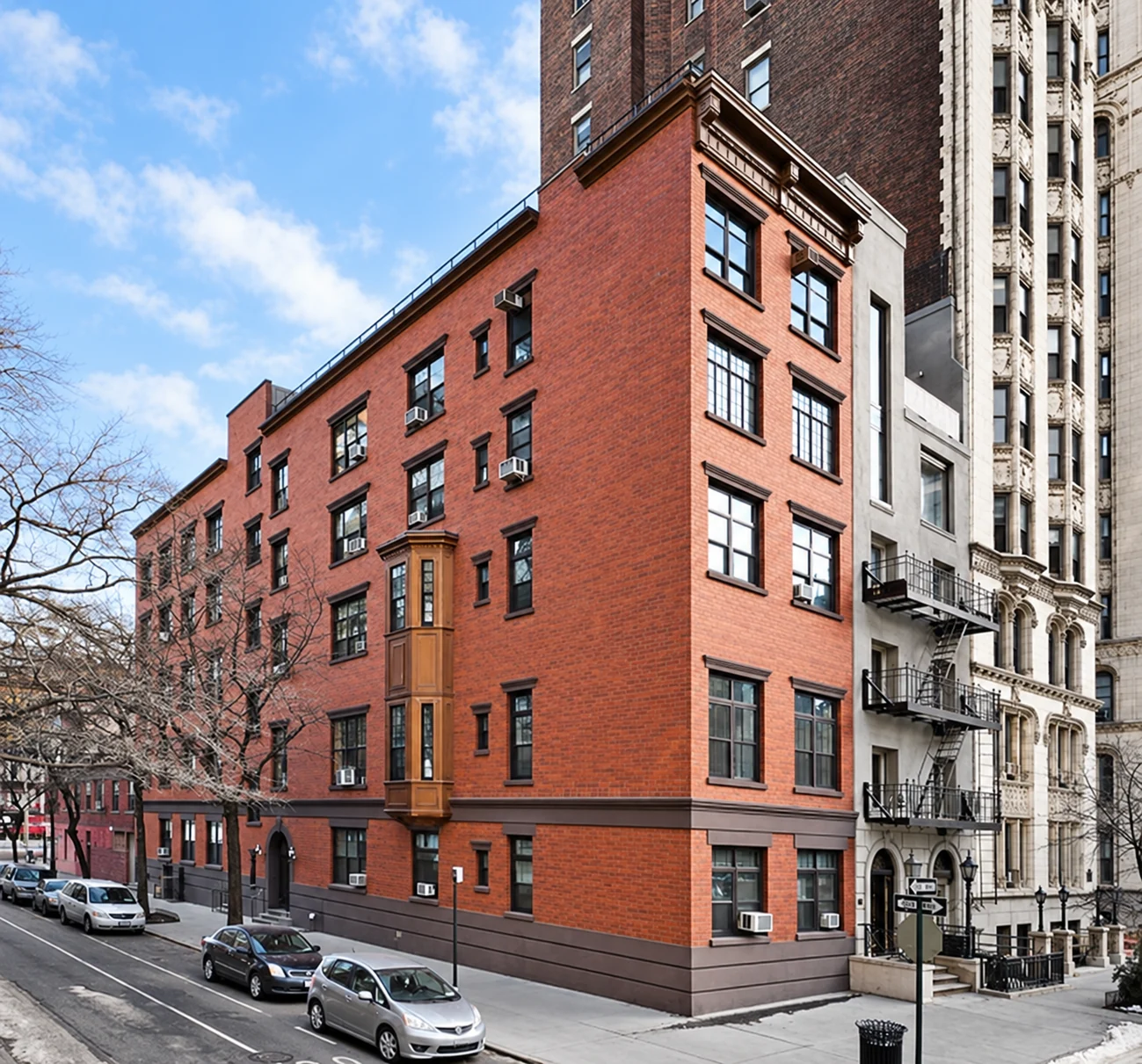 The former five-story red-brick building at 38 Gramercy Park, with copper bays and cornice, seen from the corner.