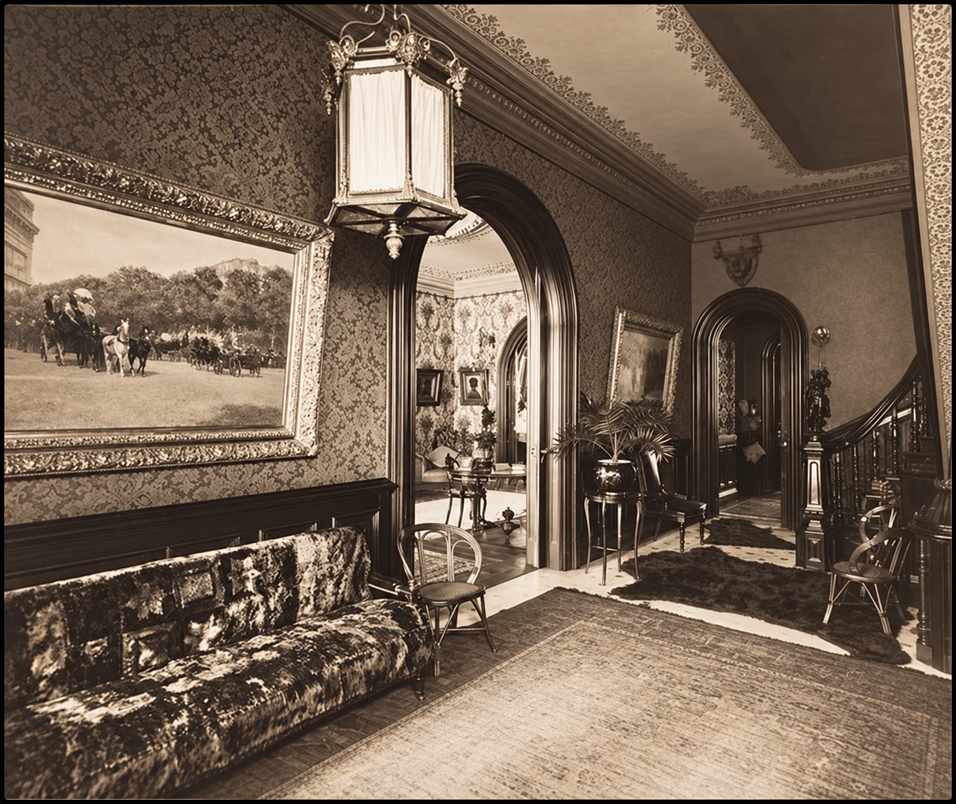 The hall at 131 East 21st Street in 1895, with patterned walls, paintings, a hanging lantern and a curved staircase.