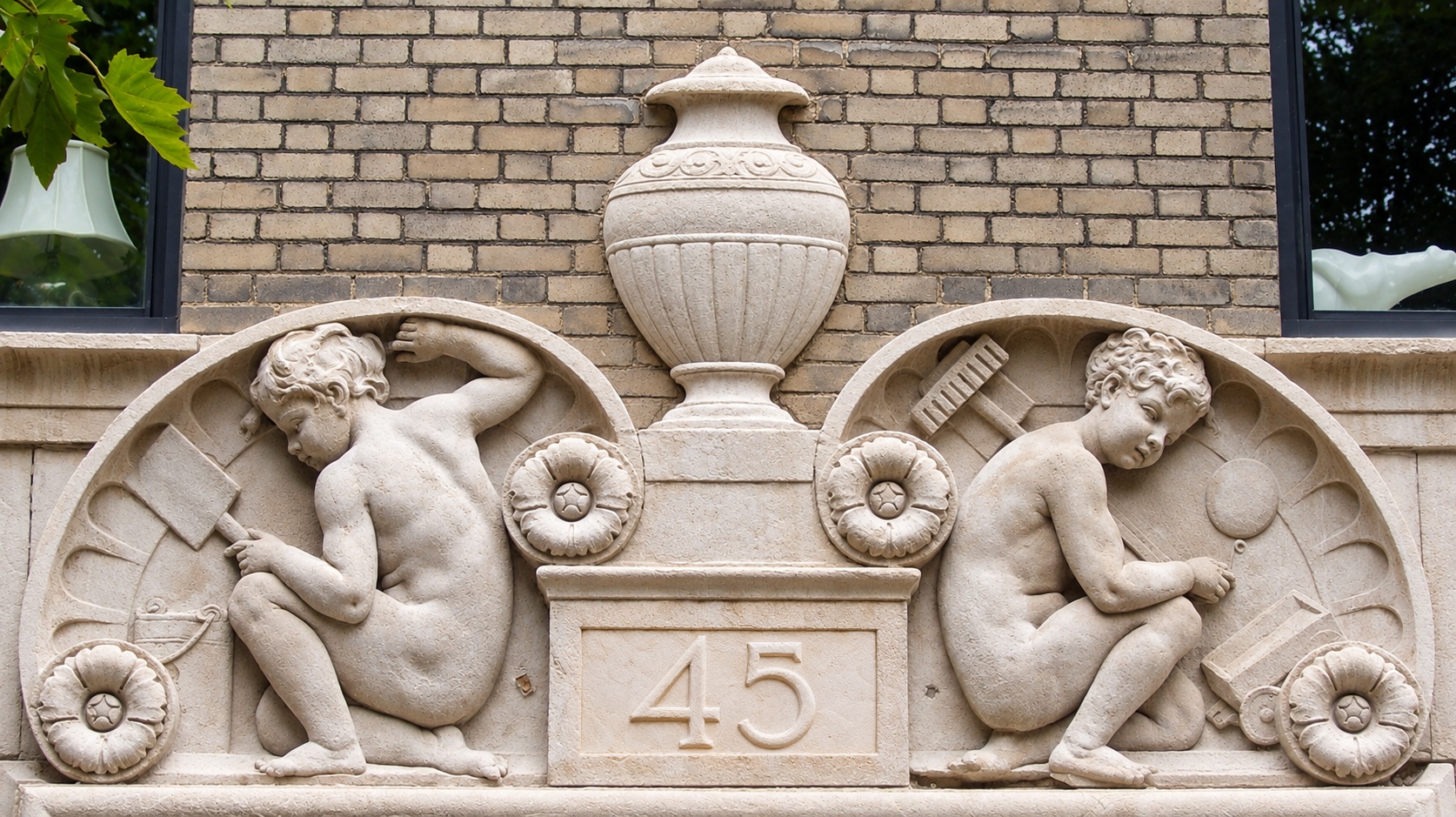 Two reclining carved figures flanking a central urn above the entrance to 45 Gramercy Park North.
