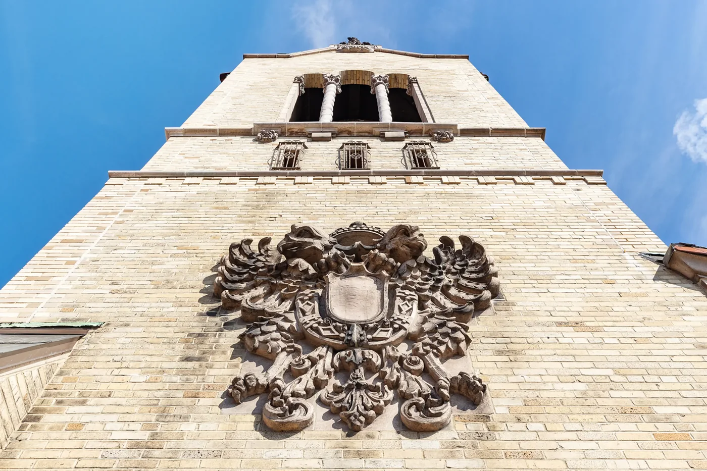 A terra-cotta cartouche below the tall triple arches of the rooftop tower.