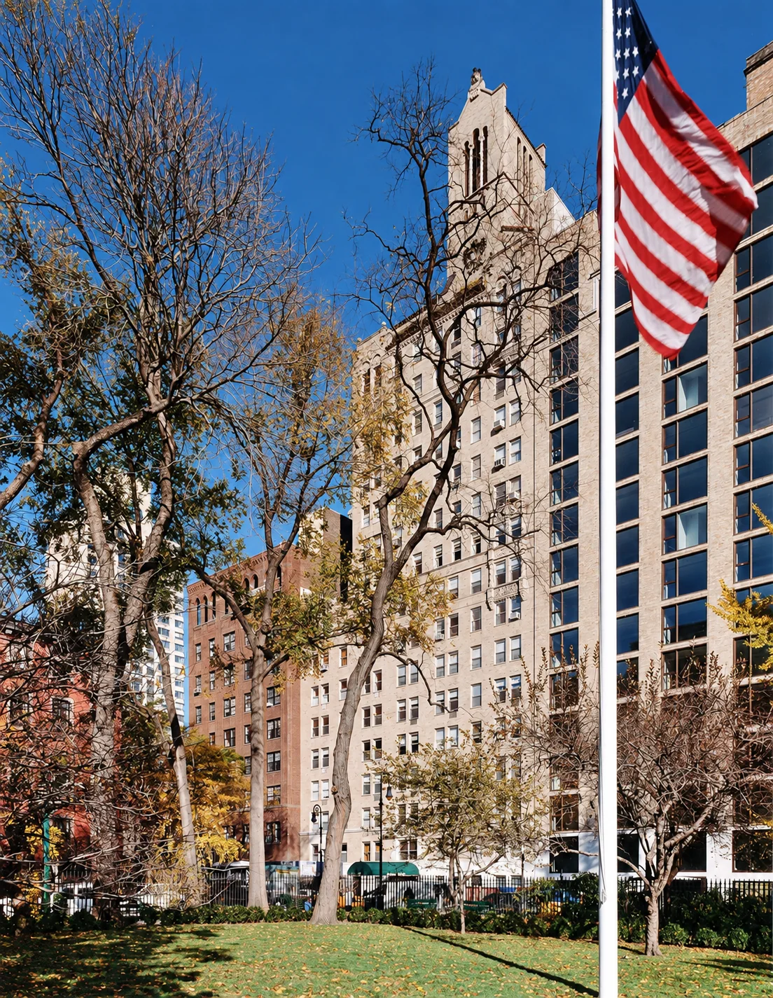 The park-facing facade of 60 Gramercy Park North, with trees and a flag in the foreground.