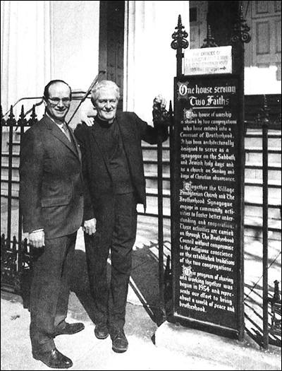 Rabbi Irving Block and the Reverend Jesse Stitt beside the sign for the Village Presbyterian Church and Brotherhood Synagogue.