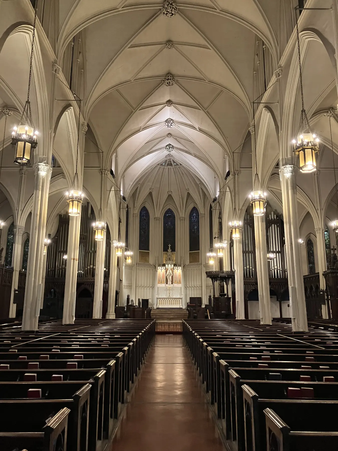 The center aisle, wooden pews, pointed arches and vaulted ceiling of Calvary, looking toward the altar.