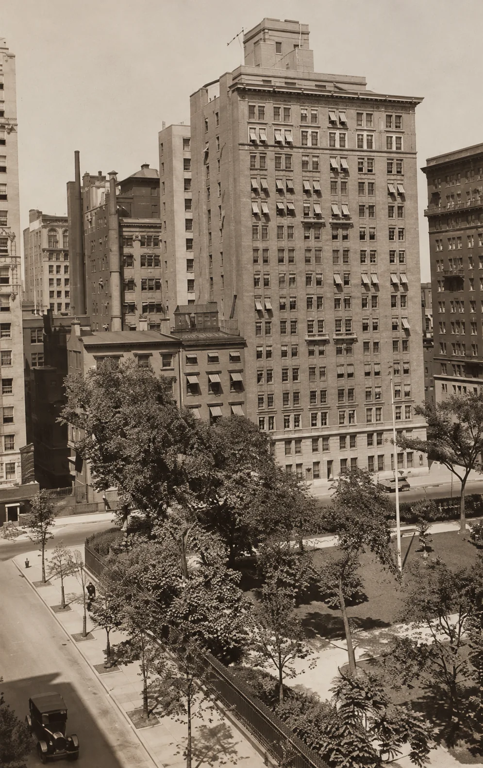 Historic elevated photograph of the Gramercy Park Hotel, with neighboring buildings, awnings, and the trees and paths of Gramercy Park below.