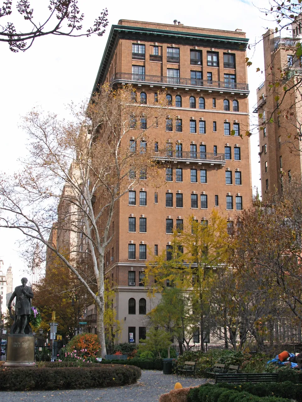 One Lexington Avenue seen across Gramercy Park in autumn, with the Edwin Booth statue and garden in the foreground.