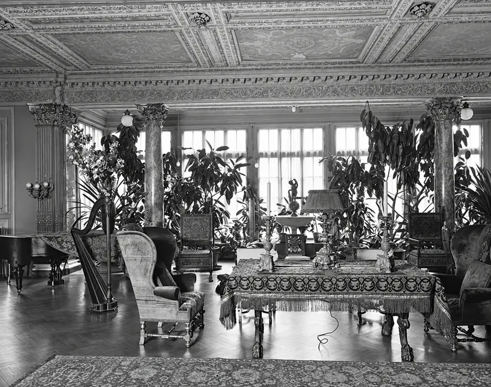 An ornate room in Henry Poor’s house with a harp, marble columns, upholstered furniture and plants beside the windows.