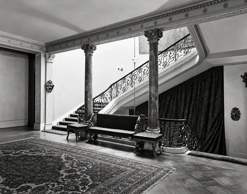 The stair hall in Henry Poor’s residence, with marble columns, a carved settee and ornamental iron balustrades.