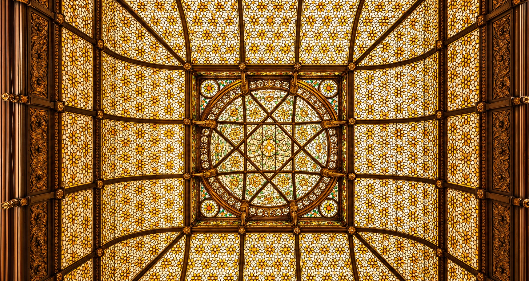 Centered view of the amber stained-glass dome attributed to Donald MacDonald, with a geometric central medallion and richly patterned glass.
