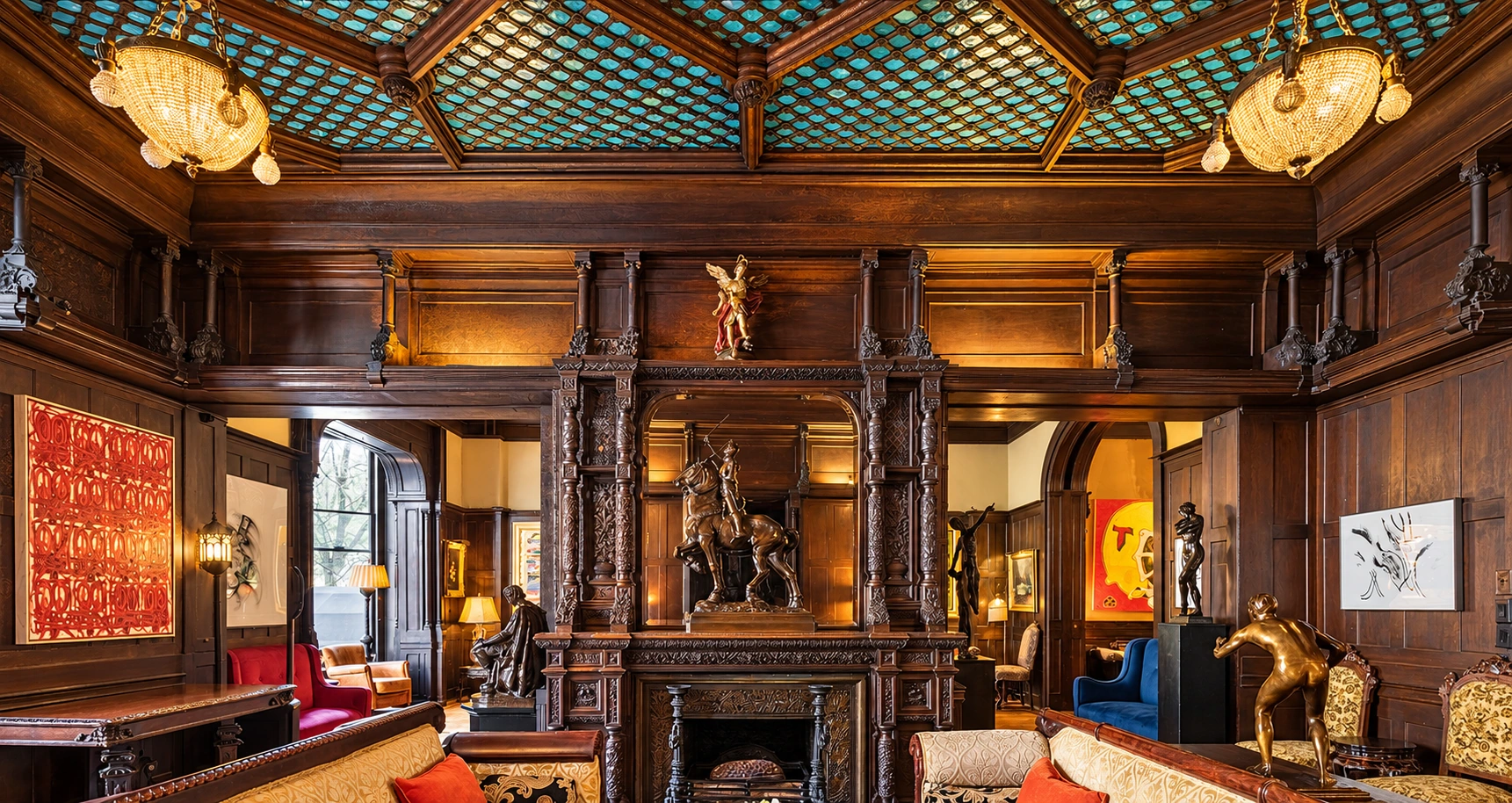 Carved wooden fireplace and mirror surround in the National Arts Club parlors, with sculpture, richly paneled walls and turquoise ceiling tiles.