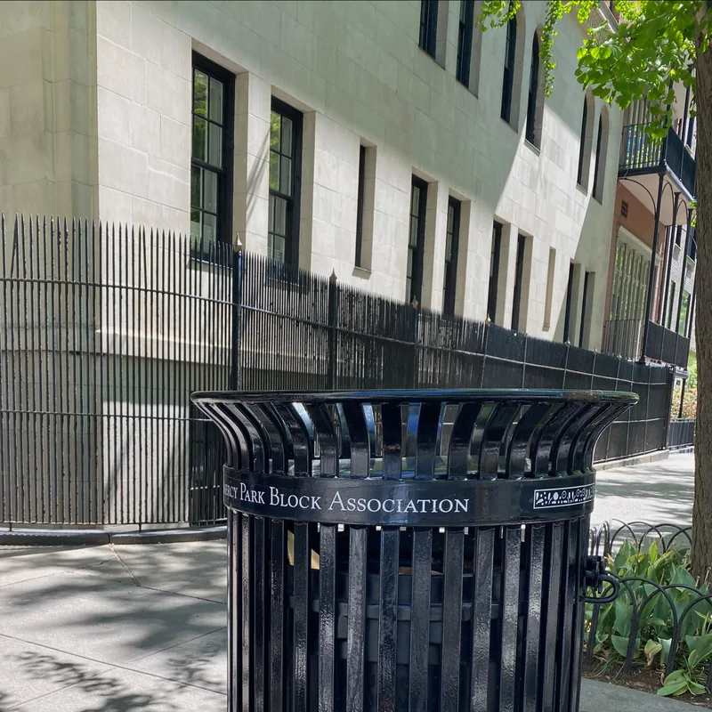 The litter basket emptied beside the building fence.