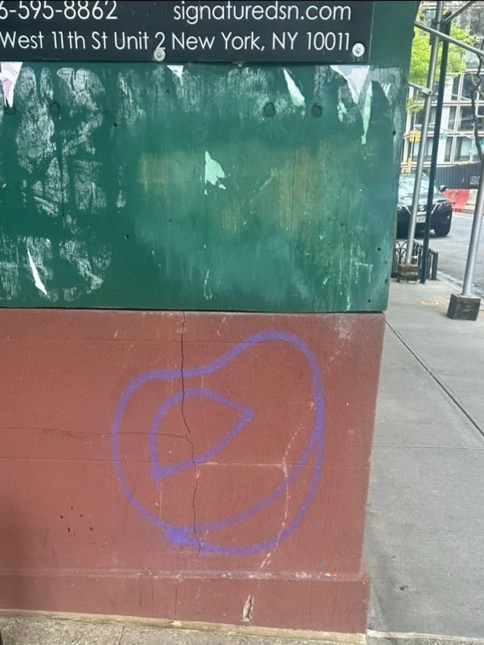 Purple graffiti on the lower part of a two-tone construction wall.