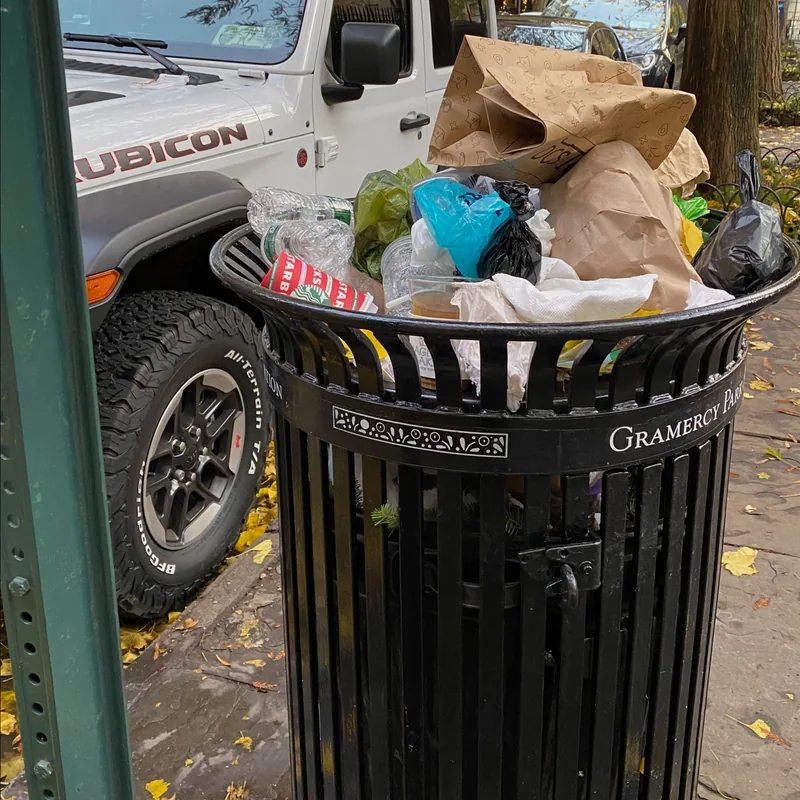 An overflowing GPBA litter basket at the curb.