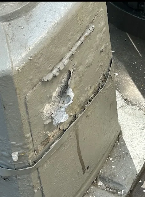 Peeling paint on the base of a gray lamppost.