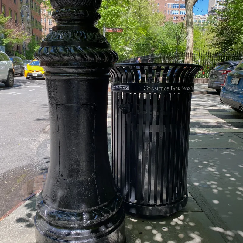The lamppost base repainted black beside the litter basket.