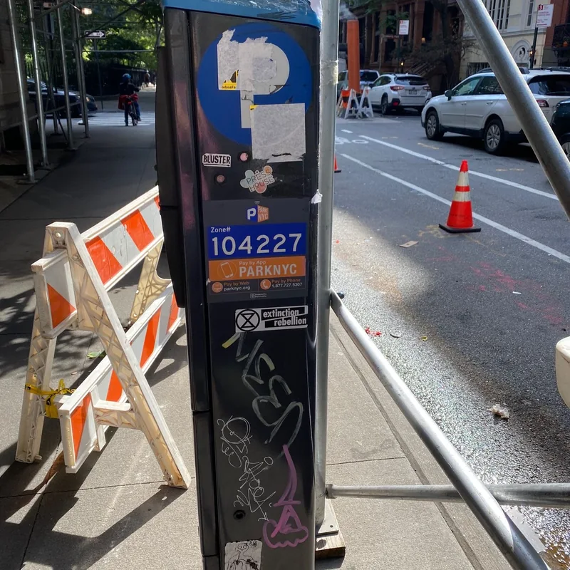 Graffiti and stickers on parking meter 104227 beside scaffolding.