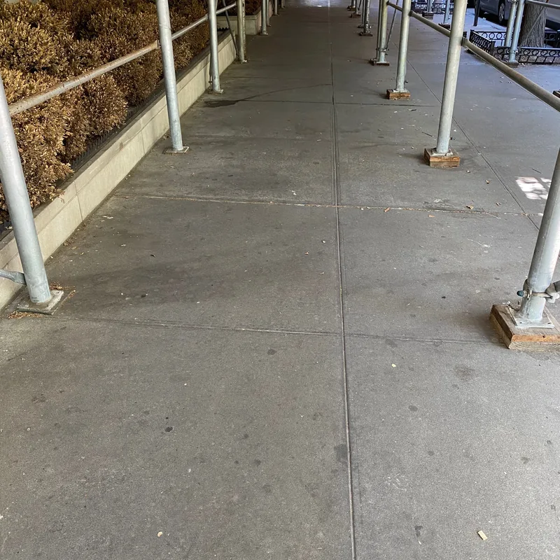 The sidewalk swept clear beneath the scaffolding.