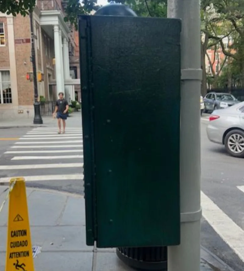 The traffic control box repainted green beside the crosswalk.