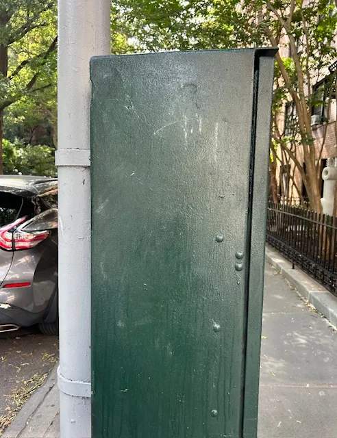 The traffic control box with the white graffiti painted over.