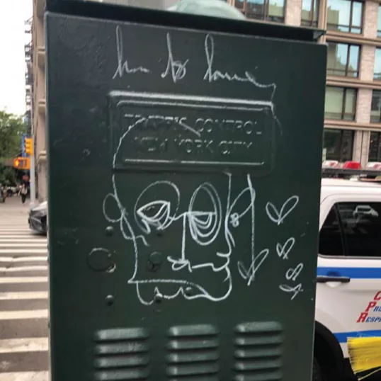 White graffiti across a green traffic control cabinet.