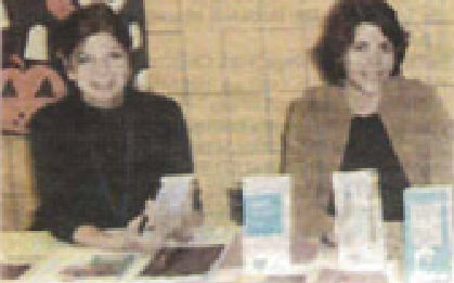 Two volunteers sit behind a table of information leaflets.