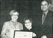 Three people hold a framed recognition at HSI’s anniversary luncheon.