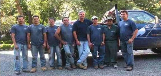 The landscape crew stands together beside a vehicle.