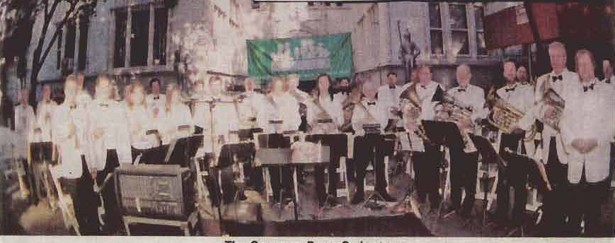 The Gramercy Brass Orchestra stands together on the outdoor concert stage.