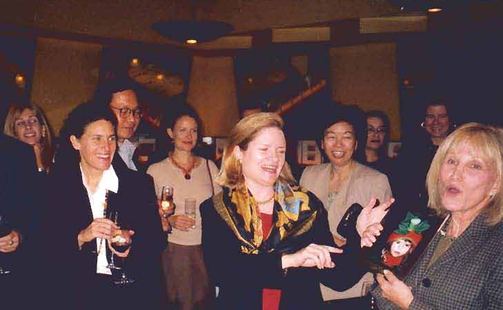 Neighbors gather around Susan Sutherland and Arlene Harrison at the reception.