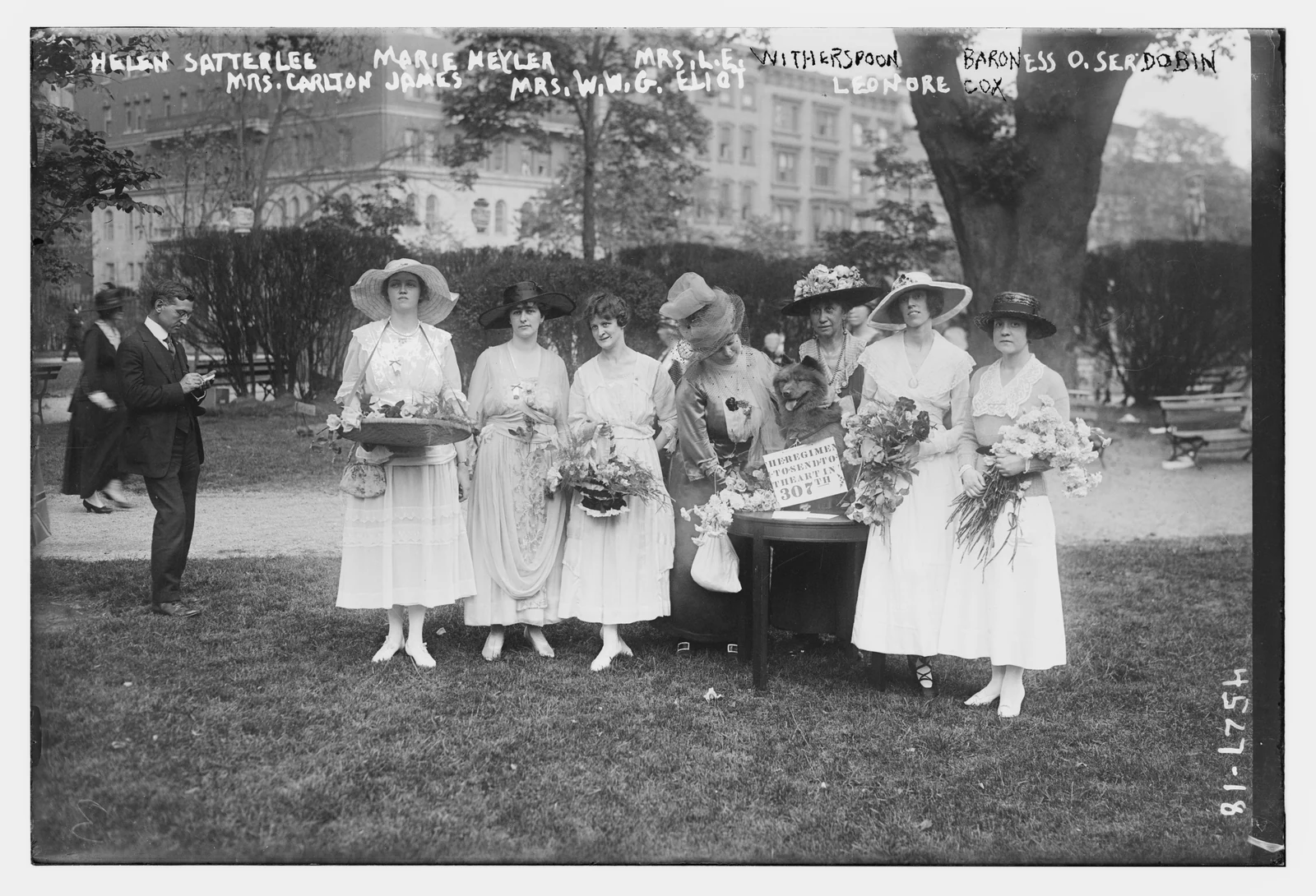 Women holding bouquets gather around a table at the 1918 garden party, with handwritten identifications preserved on the negative.