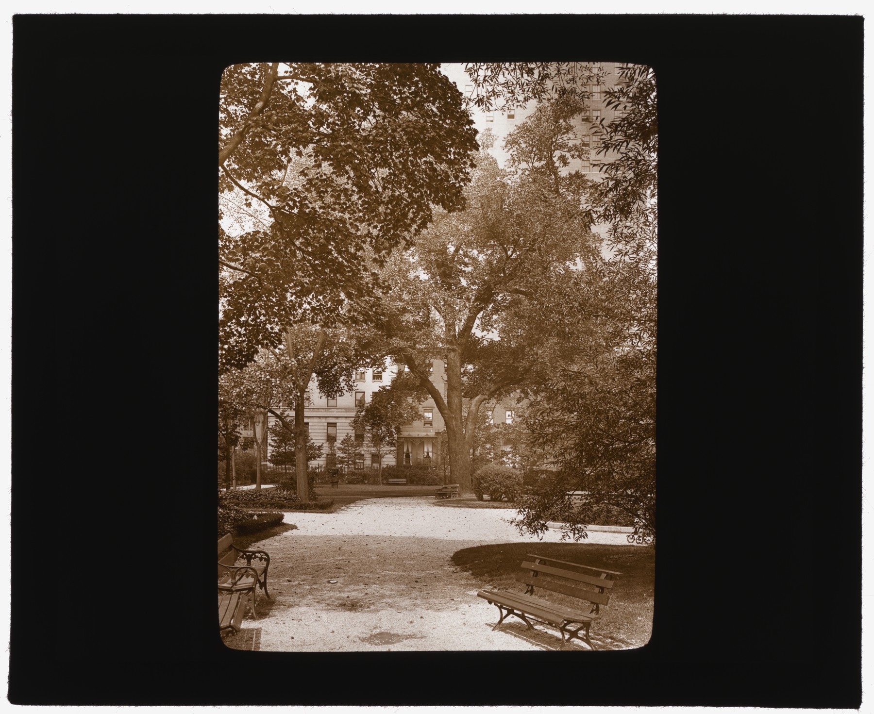 A sepia lantern slide showing curving paths, benches and mature trees inside Gramercy Park, about 1922.