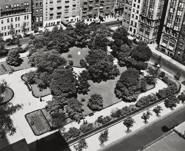 An overhead view of Gramercy Park’s trees, lawns, planting beds and curving paths, with the surrounding buildings beyond the fence.