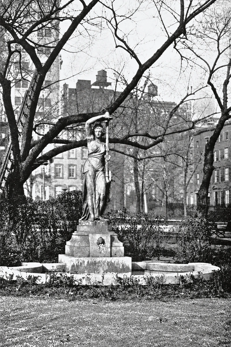 The eastern nymph fountain beneath bare branches, with buildings beyond the Park.