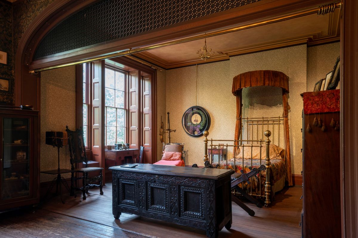 Edwin Booth’s bedroom with its brass canopy bed, carved chest and restored wallpaper, seen through the arch from the sitting room.