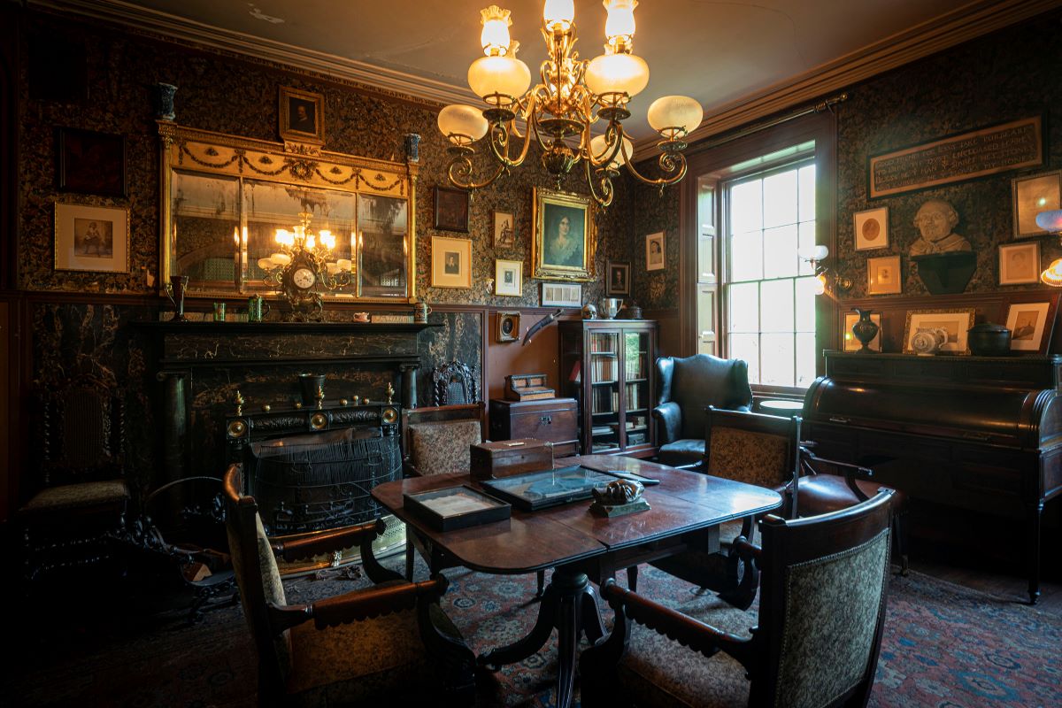 Booth’s sitting room with its fireplace, chandelier, roll-top desk, framed portraits and a table of personal keepsakes.